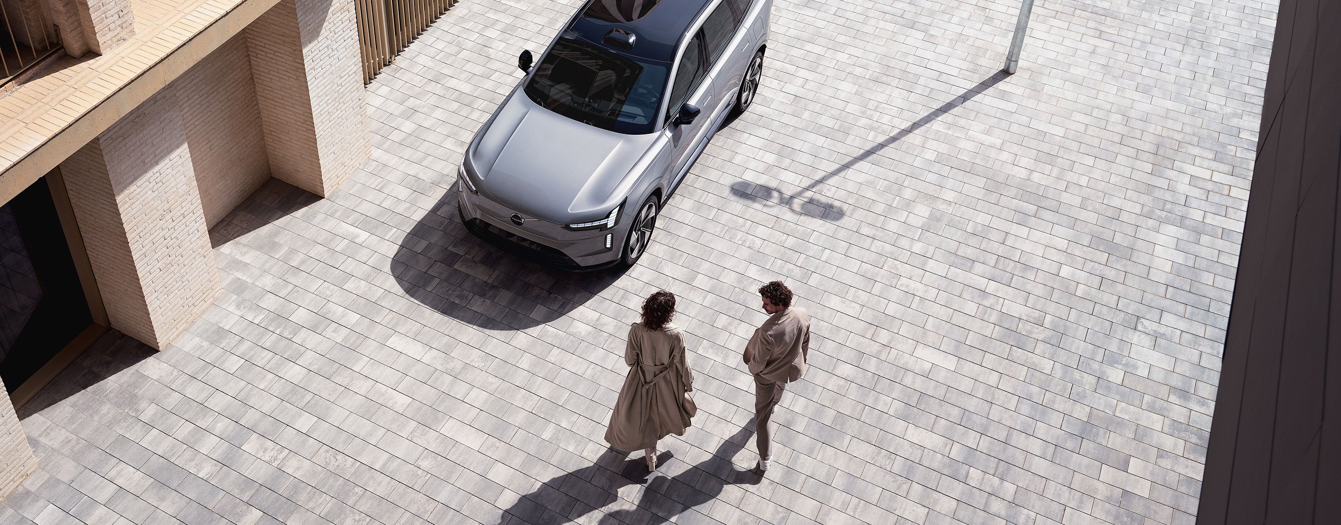 Drei Menschen stehen an Autohaus um den Volvo XC40 Pure Electric