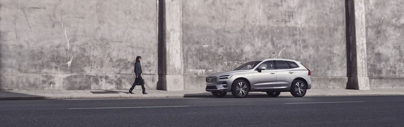 Frau geht auf Volvo XC60 Plug-in Hybrid zu