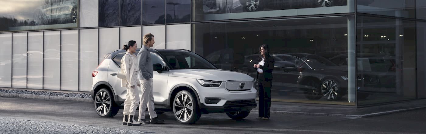 Drei Menschen stehen an Autohaus um den Volvo XC40 Pure Electric